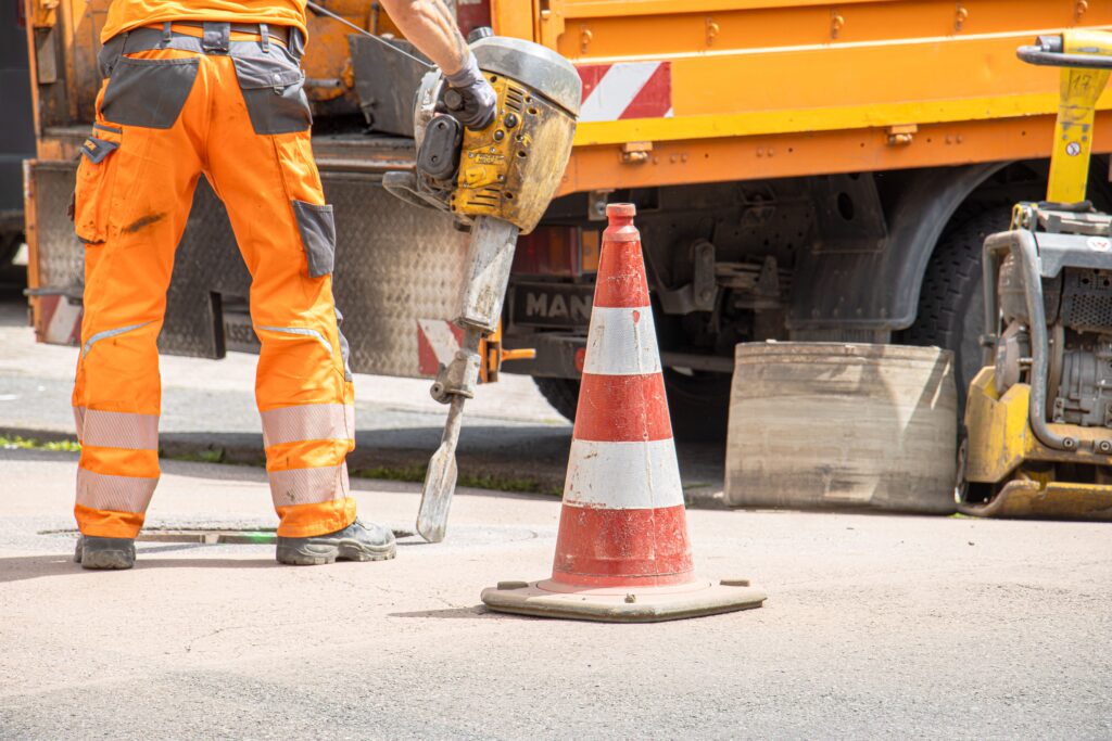 Vacatures bij Stedin: medewerker in oranje werkkleding met een breekhamer bij werkzaamheden in de straat