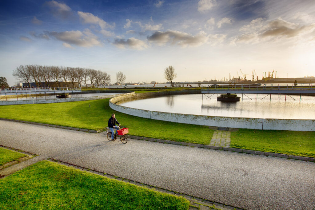 Vacatures bij het waterschap: fietser bij de bezinktanks van een rioolwaterzuivering
